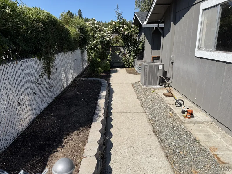 The same side yard bed stripped back to clean soil with the walkway swept after a Peak Landscaping cleanup in Southern Oregon
