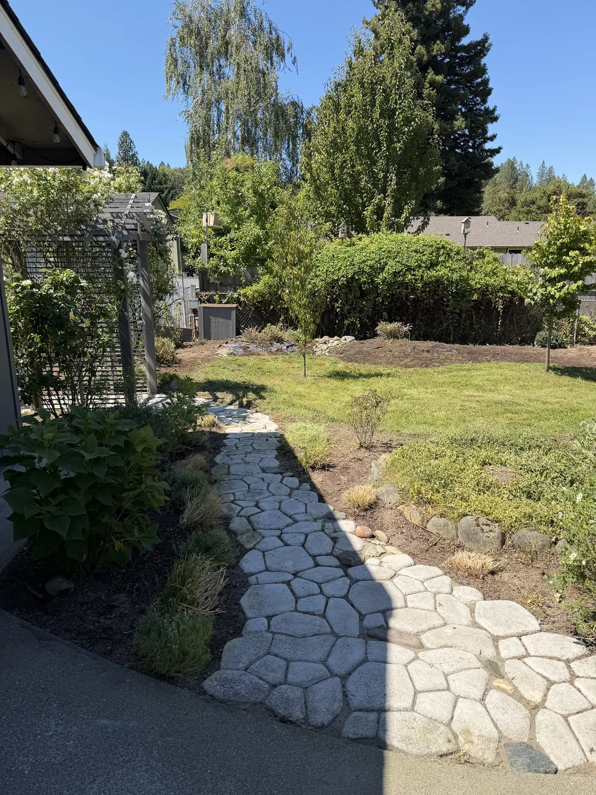 The same flagstone path fully exposed, with the beds mulched and the lawn mowed, after Peak Landscaping restored the yard in Southern Oregon