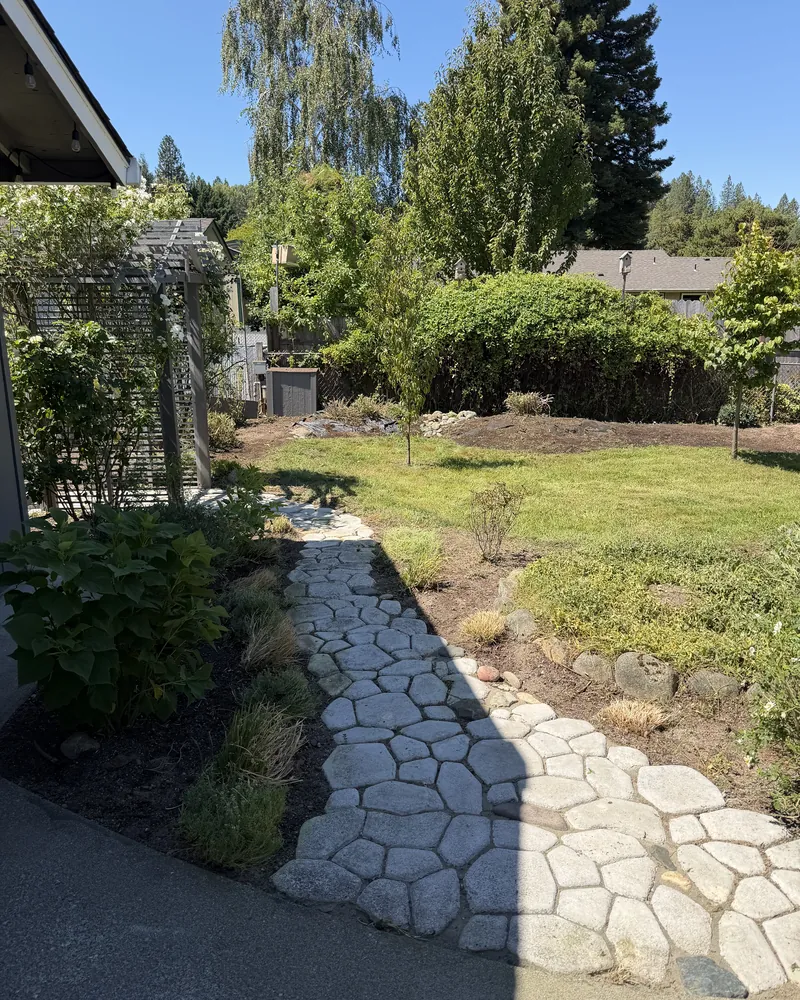 Backyard flagstone path fully exposed with mulched beds and a mowed lawn after Peak Landscaping restored the yard in Southern Oregon