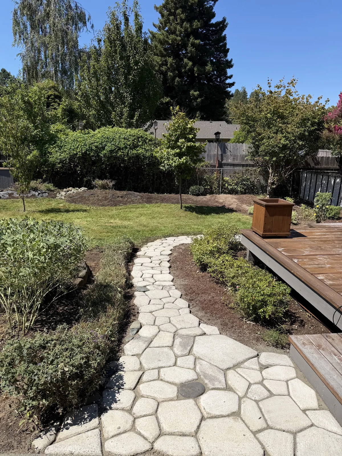The same backyard after Peak Landscaping mowed the lawn, edged the stone path and mulched the planting beds in Southern Oregon